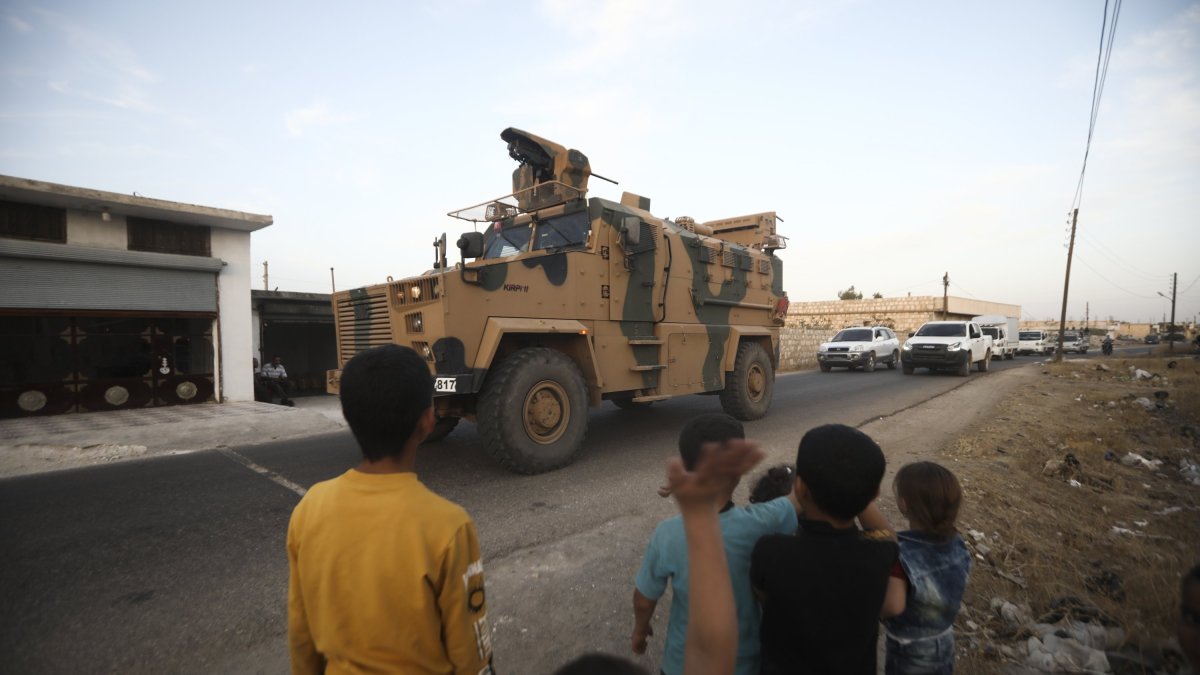 Children wave as a Turkish military convoy drives through the village of Urum al-Jawz, Idlib, Syria, Oct. 20, 2020. (AP Photo)