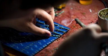 A volunteer uses a soldering iron to build a Power Kit power bank for the Ukrainian military, made from donated lithium batteries of used e-cigarettes, at a non-profit organization's warehouse, Kyiv, Ukraine, July 1, 2023. (Getty Images Photo)