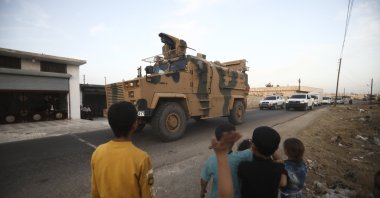 Children wave as a Turkish military convoy drives through the village of Urum al-Jawz, Idlib, Syria, Oct. 20, 2020. (AP Photo)