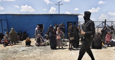 A U.S.-backed PKK/YPG terrorist passes in front of family members of suspected Daesh terrorists who are waiting to be transferred from the al-Hol camp, Hassakeh province, Syria, May 8, 2024. (AP Photo)
