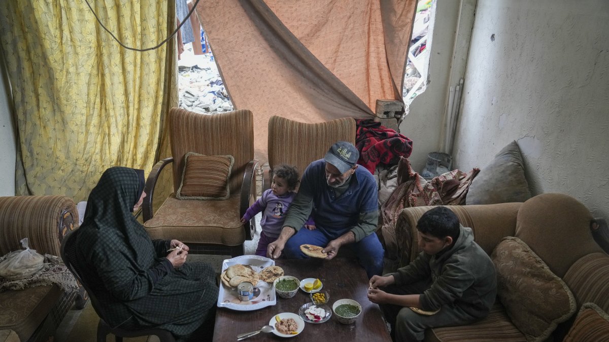 Khalid Nassar (2nd R) sits with his wife, Khadra Abu Libda, and his grandchildren for lunch, with fabric covering the hole in a wall of their destroyed house in the Jabaliya refugee camp, Gaza Strip, Palestine, Feb. 9, 2025. (AP Photo)