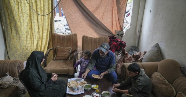 Khalid Nassar (2nd R) sits with his wife, Khadra Abu Libda, and his grandchildren for lunch, with fabric covering the hole in a wall of their destroyed house in the Jabaliya refugee camp, Gaza Strip, Palestine, Feb. 9, 2025. (AP Photo)