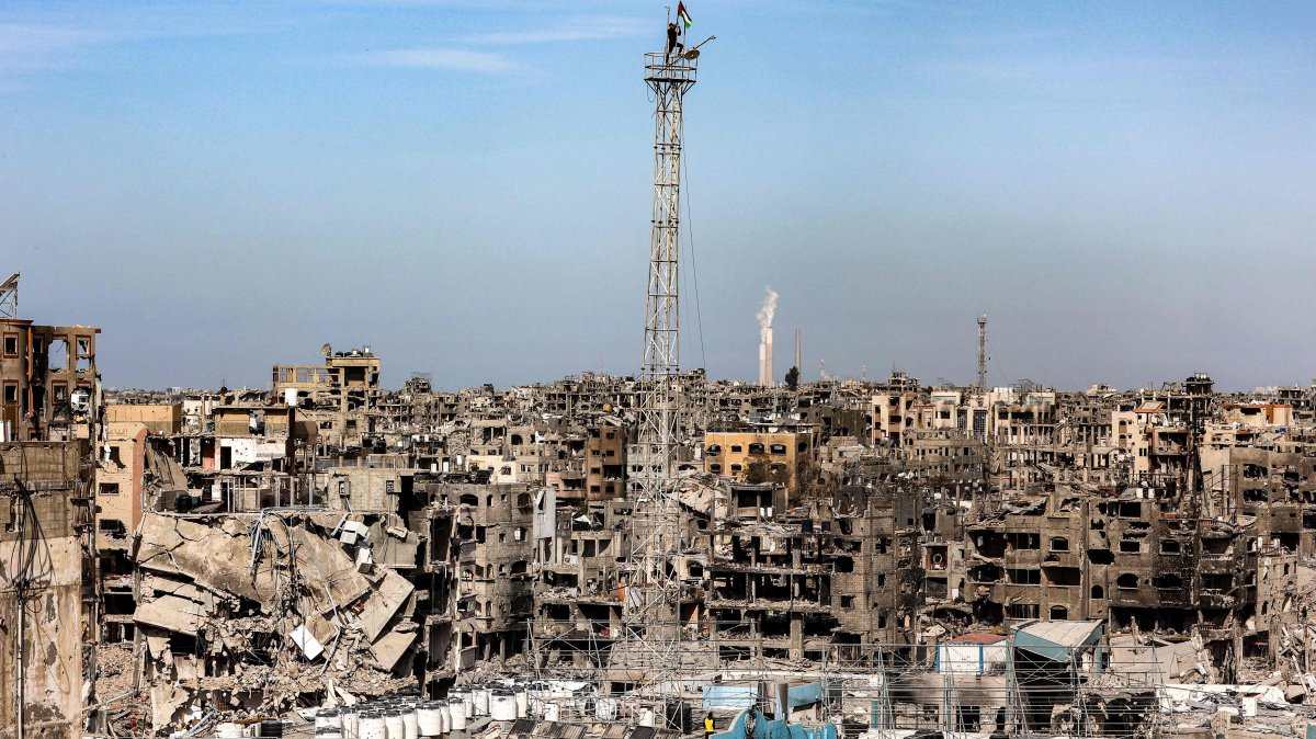 A man fixes a Palestinian flag atop the antenna of a destroyed building that was a clinic for the United Nations Relief and Works Agency for Palestine Refugees (UNRWA) at the Jabalia camp in the northern Gaza Strip, Jan. 19, 2025. (AFP Photo)