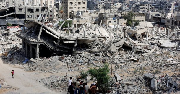 Palestinians sit next to the rubble of houses destroyed by Israel in Khan Younis in the southern Gaza Strip Oct. 7, 2024. (Reuters File Photo)
