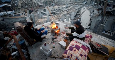 Palestinians sit next to a fire among the rubble of buildings destroyed during the Israeli offensive, at Jabalia refugee camp, northern Gaza Strip, Palestine, Feb. 17, 2025. (Reuters Photo)