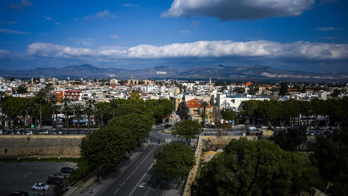 A group of women (bottom) walk along a street as a giant flag of the Turkish Republic of Northern Cyprus (TRNC) is seen painted on the side of the Girne (Kyrenia) mountain range, Lefkoşa (Nicosia), TRNC, Feb. 9, 2025. (AFP Photo)