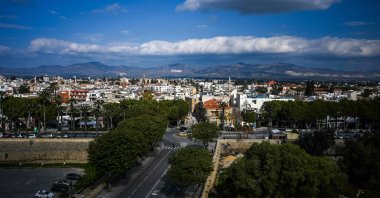 A group of women (bottom) walk along a street as a giant flag of the Turkish Republic of Northern Cyprus (TRNC) is seen painted on the side of the Girne (Kyrenia) mountain range, Lefkoşa (Nicosia), TRNC, Feb. 9, 2025. (AFP Photo)