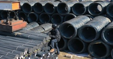 A worker climbs a stack of steel rods at a wholesale steel market in Shenyang, China, Feb. 19, 2025. (AFP Photo)