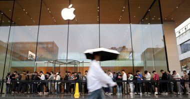 People line up outside an Apple store on a rainy day as the new iPhone 16 series smartphones go on sale, in Beijing, China, Sept. 20, 2024. (Reuters Photo)