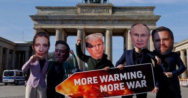 Activists wearing masks of (L-R) co-leader and main candidate of the far-right Alternative for Germany (AfD) party Alice Weidel, Tesla and SpaceX CEO Elon Musk, U.S. President Donald Trump, Russian President Vladimir Putin and U.S. Vice President JD Vance hold up a placard that reads &quot;More Warming More War&quot; as they stage a protest in front of the landmark Brandenburg Gate, Berlin, Germany, Feb. 20, 2025. (AFP Photo)
