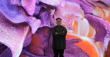Artist Refik Anadol poses in front of display with his artificial intelligence art work inside the Davos Congress Center, Davos, Switzerland, Jan. 16, 2023. (AP Photo)