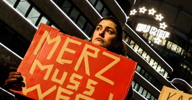 A woman holds a banner that reads &quot;Merz must go&quot; against Chair of the Christian Democratic Union (CDU) party and chancellor candidate Friedrich Merz during an election campaign event, Berlin, Germany, Feb. 20, 2025. (EPA Photo)