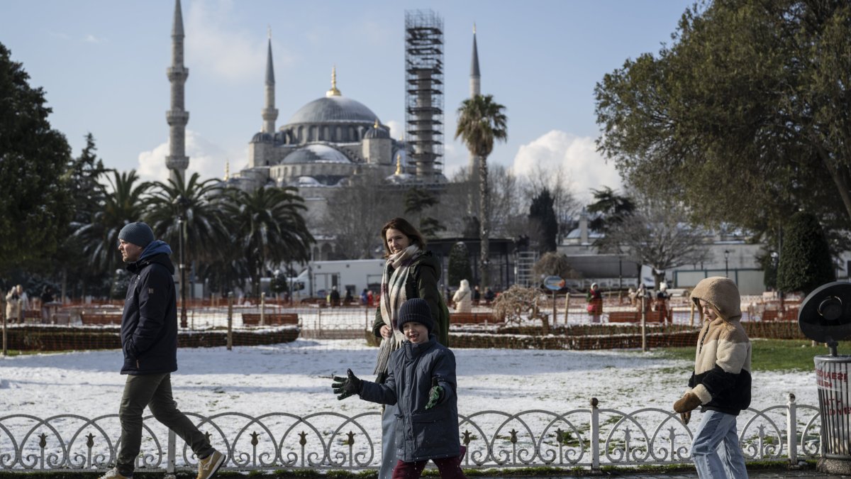A family enjoys the snowy winter moments at Sultanahmet Square, with the historic Blue Mosque (under restoration) visible in the background, Istanbul, Türkiye, Feb. 23, 2025. (AA Photo)