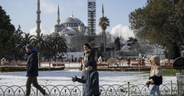 A family enjoys the snowy winter moments at Sultanahmet Square, with the historic Blue Mosque (under restoration) visible in the background, Istanbul, Türkiye, Feb. 23, 2025. (AA Photo)