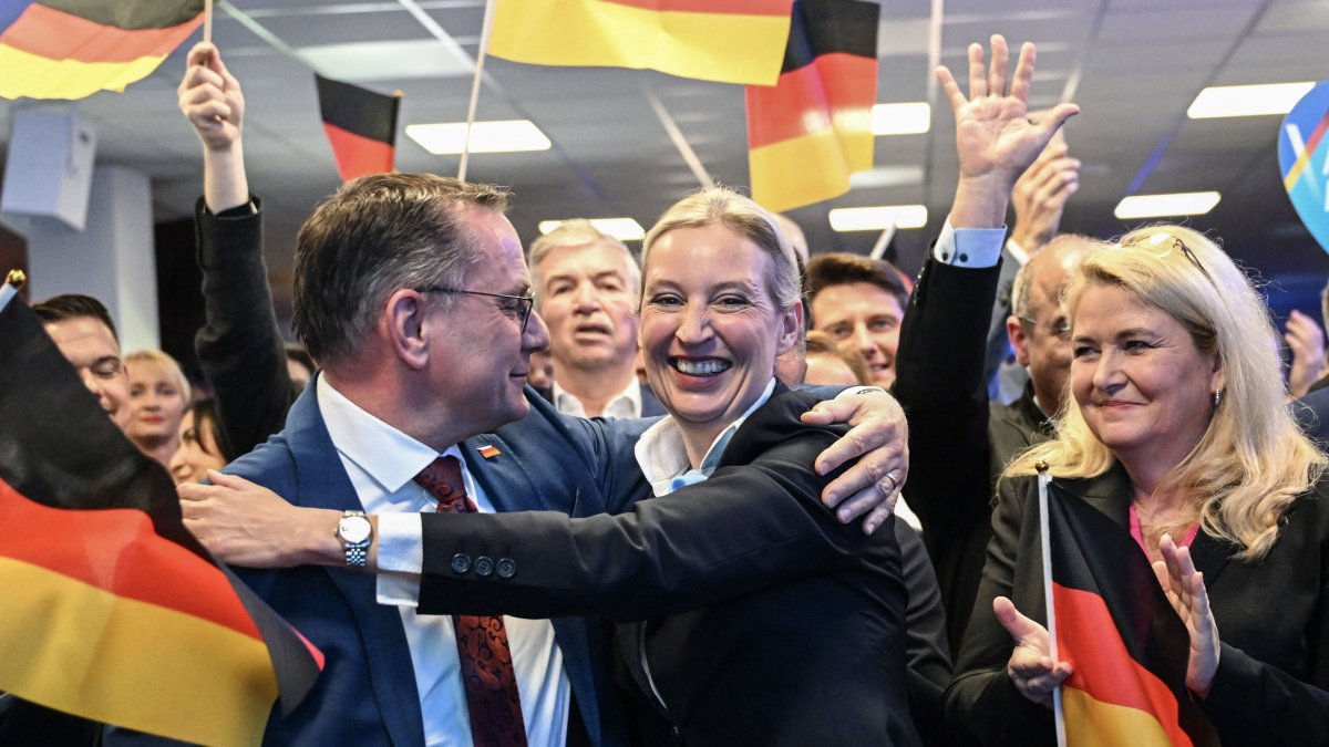 Co-leaders of Germany&#039;s far-right Alternative for Germany (AfD) party Alice Weidel (C) and Tino Chrupalla (L) hug during the electoral evening, Berlin, Germany, Feb. 23, 2025. (AFP Photo)