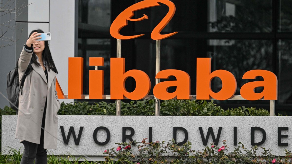 A woman poses for a selfie next to signage for e-commerce giant Alibaba, Xuhui district, Shanghai, China, Feb. 22, 2025. (AFP Photo)