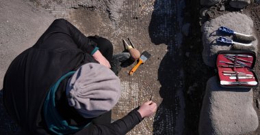 An archaeologist uncovers mosaic tiles in &quot;Mosaic House&quot; in the ancient city of Pergamon, Izmir, western Türkiye, Feb. 24, 2025. (AA Photo)
