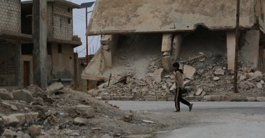 A boy walks along a street with destroyed buildings in the town of al-Hafta, east of Manbij, Syria, Feb. 25, 2025. (AA Photo)