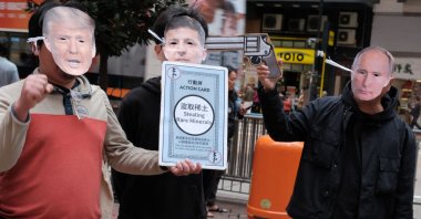 (From L-R) Activists wearing masks of U.S. President Donald Trump, Ukrainian President Volodymyr Zelenskyy and Vladimir Putin take part in a demonstration in Hong Kong, Feb. 23, 2025. (AFP Photo)