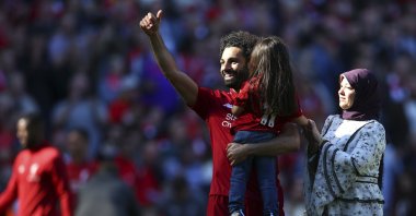 Liverpool's Mohamed Salah (L), accompanied by his wife Magi greets supporters while holding his daughter Makkah at the end of the English Premier League match against Wolves at the Anfield stadium, Liverpool, U.K., May 12, 2019. (AP Photo)