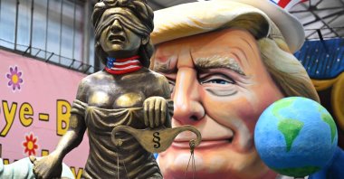 A carnival float showing Donald Trump keeping the Statue of Liberty and Justice on a leash as he is showing a finger to the world, in Cologne, Germany, Feb. 25, 2025. (AFP Photo)