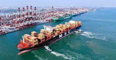 An aerial view shows a container ship being guided to its berth by tugboats at Qingdao port in China’s eastern Shandong province, Feb. 23, 2025. (AFP Photo)