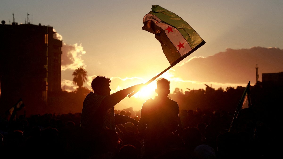 A person holds up the flag adopted by the new Syrian rulers as people celebrate after fighters of the ruling Syrian body ousted Bashar Assad, Damascus, Syria, Dec. 13, 2024. (Reuters Photo)