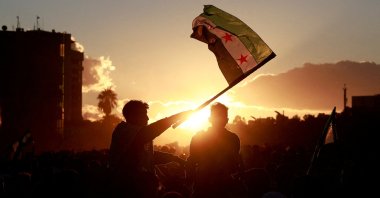 A person holds up the flag adopted by the new Syrian rulers as people celebrate after fighters of the ruling Syrian body ousted Bashar Assad, Damascus, Syria, Dec. 13, 2024. (Reuters Photo)