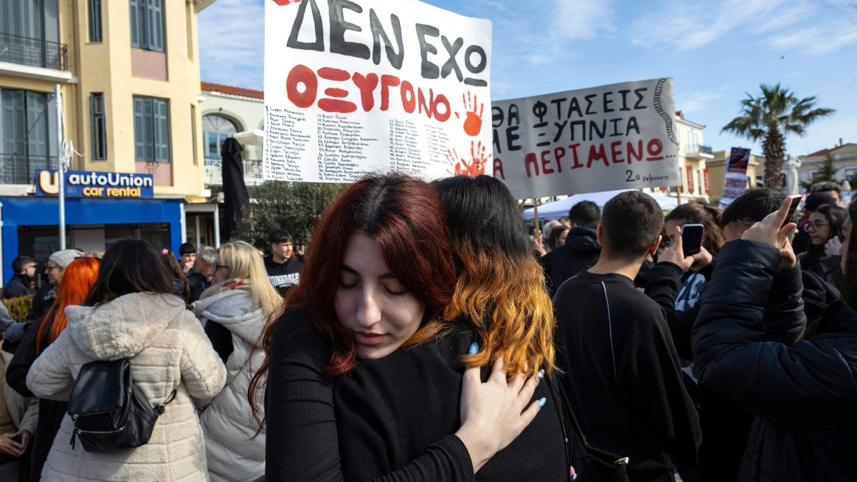 Protesters embrace next to a placard to demand justice for the victims of a train crash, Lesvos island, Greece, Feb. 28, 2025. (EPA Photo)
