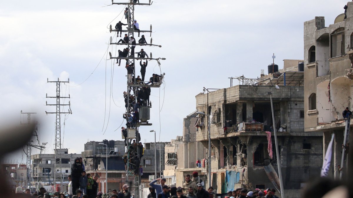 Palestinians climb over an electricity pole to get a glimpse of the release of three Israeli hostages as part of the seventh hostage-prisoner swap, in Nuseirat in the central Gaza Strip, Feb. 22, 2025. (AFP Photo)