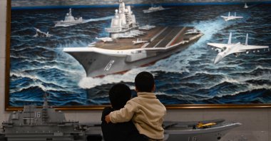 People look at a model and painting of China’s Liaoning aircraft carrier at the Military Museum in Beijing, China, March 2, 2025. (AFP Photo)