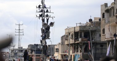 Palestinians climb over an electricity pole to get a glimpse of the release of three Israeli hostages as part of the seventh hostage-prisoner swap, in Nuseirat in the central Gaza Strip, Feb. 22, 2025. (AFP Photo)