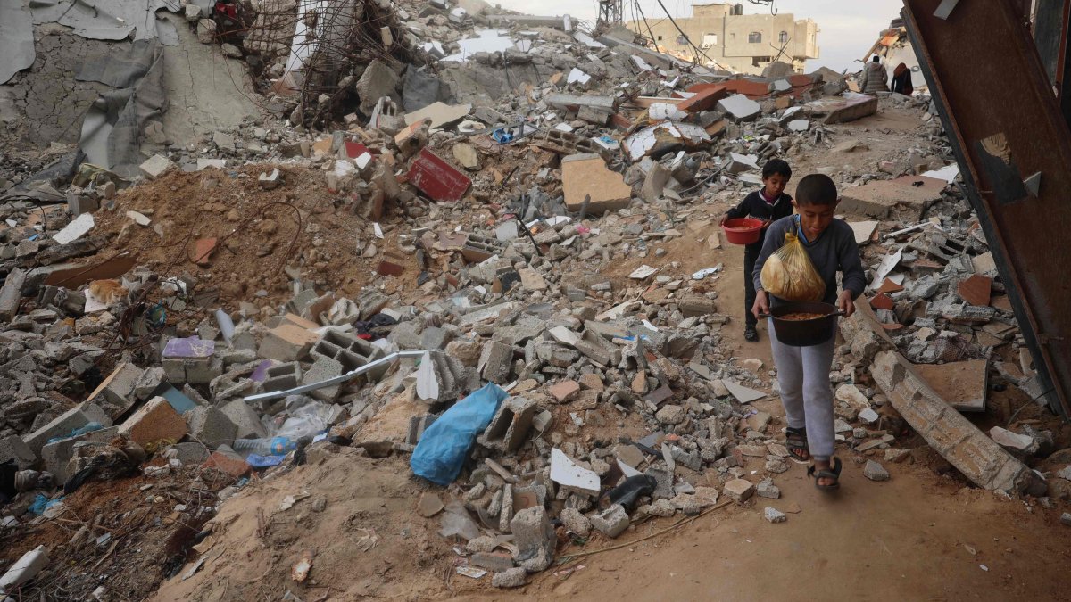 Palestinian children carry food past destroyed buildings at the Nuseirat refugee camp in the central Gaza Strip, Palestine, March 3, 2025. (AFP Photo)
