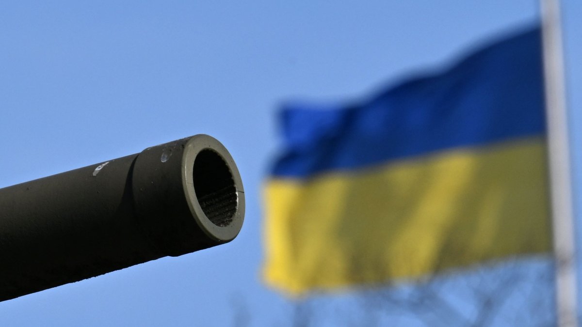 The gun barrel of a Russian T-34 tank included in the Soviet War Memorial is backdropped by a Ukrainian flag on the Reichstag building that houses the Bundestag (lower house of German parliament), Berlin, Germany, Feb. 24, 2025. (AFP Photo)