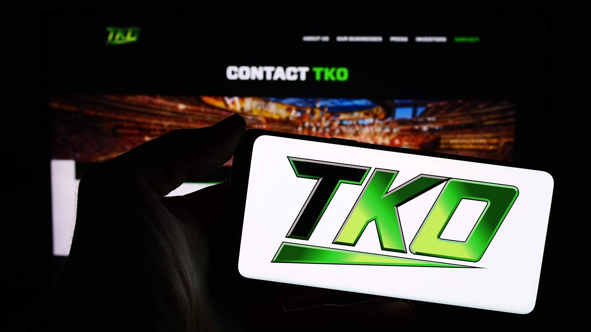 A person holding a cellphone with a logo of U.S. media company TKO Group Holdings Inc. in front of a business webpage, Stuttgart, Germany, Feb. 15, 2025. (Shutterstock Photo)