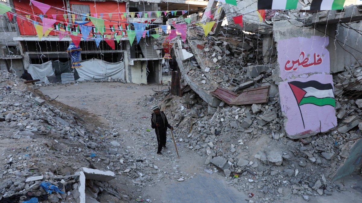 A Palestinian walks past graffiti and the rubble of buildings, ahead of the holy fasting month of Ramadan, amid a cease-fire between Israel and Hamas, in Khan Younis, in the southern Gaza Strip, Feb. 27, 2025. (Reuters File Photo)