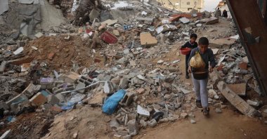 Palestinian children carry food past destroyed buildings at the Nuseirat refugee camp in the central Gaza Strip, Palestine, March 3, 2025. (AFP Photo)