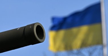 The gun barrel of a Russian T-34 tank included in the Soviet War Memorial is backdropped by a Ukrainian flag on the Reichstag building that houses the Bundestag (lower house of German parliament), Berlin, Germany, Feb. 24, 2025. (AFP Photo)