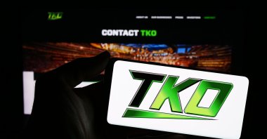 A person holding a cellphone with a logo of U.S. media company TKO Group Holdings Inc. in front of a business webpage, Stuttgart, Germany, Feb. 15, 2025. (Shutterstock Photo)