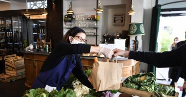 A customer buys food for take away at the L&#039;Oseille restaurant where people can also buy fresh fruits and vegetables, Paris, France, May 15, 2020. (AFP Photo)