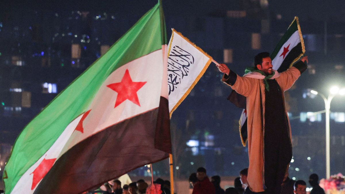 A person holds flags as people celebrate after the U.S.-backed YPG signed a deal agreeing to integrate into Syria&#039;s new state institutions, Qamishli, Syria, March 11, 2025. (Reuters Photo)