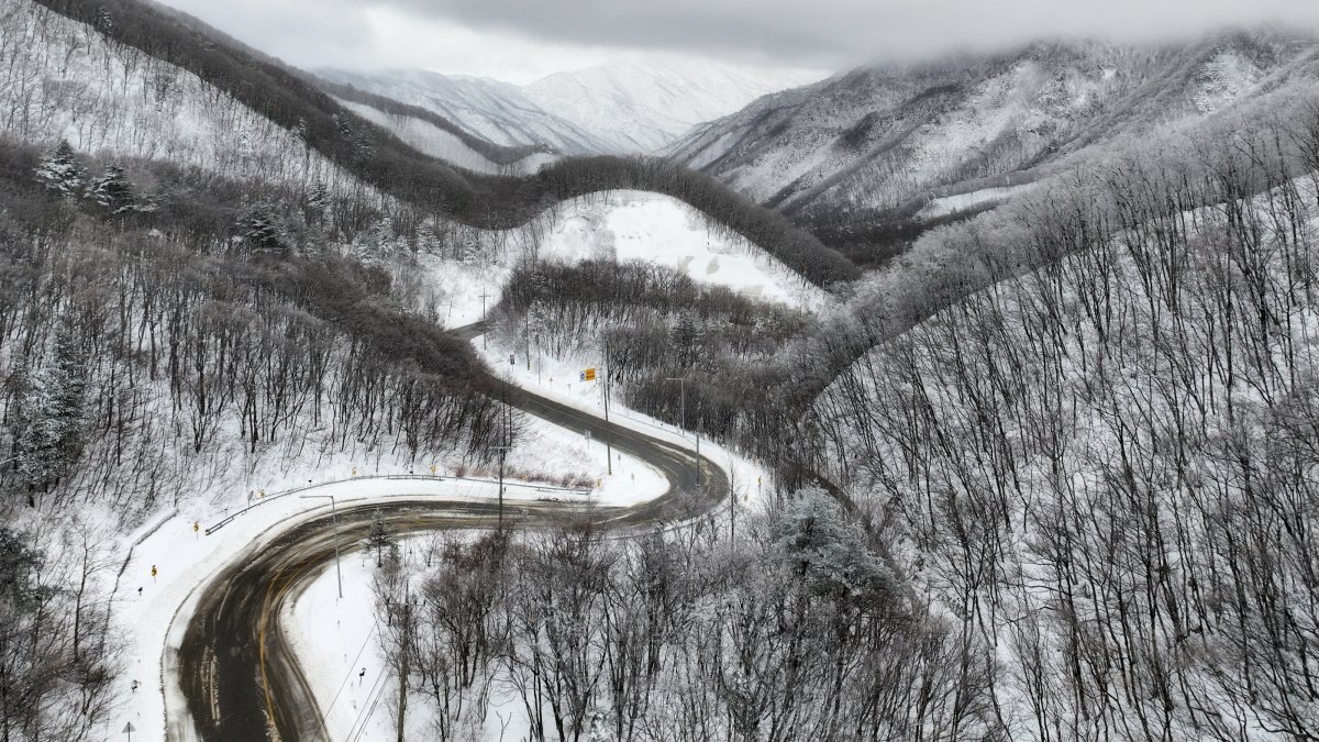 A curvy road passes through snow-covered hills and mountains in Gangneung, South Korea, March 3, 2025. (EPA Photo)