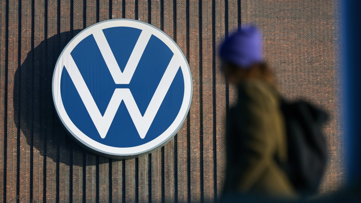 A person walks next to the logo of German car maker Volkswagen on a wall at the company&#039;s plant in Wolfsburg, Germany, March 7, 2025. (EPA Photo)
