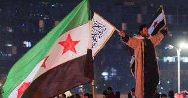 A person holds flags as people celebrate after the U.S.-backed YPG signed a deal agreeing to integrate into Syria&#039;s new state institutions, Qamishli, Syria, March 11, 2025. (Reuters Photo)