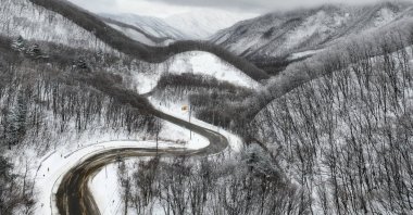 A curvy road passes through snow-covered hills and mountains in Gangneung, South Korea, March 3, 2025. (EPA Photo)