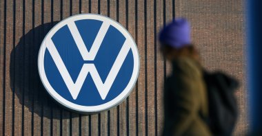 A person walks next to the logo of German car maker Volkswagen on a wall at the company&#039;s plant in Wolfsburg, Germany, March 7, 2025. (EPA Photo)