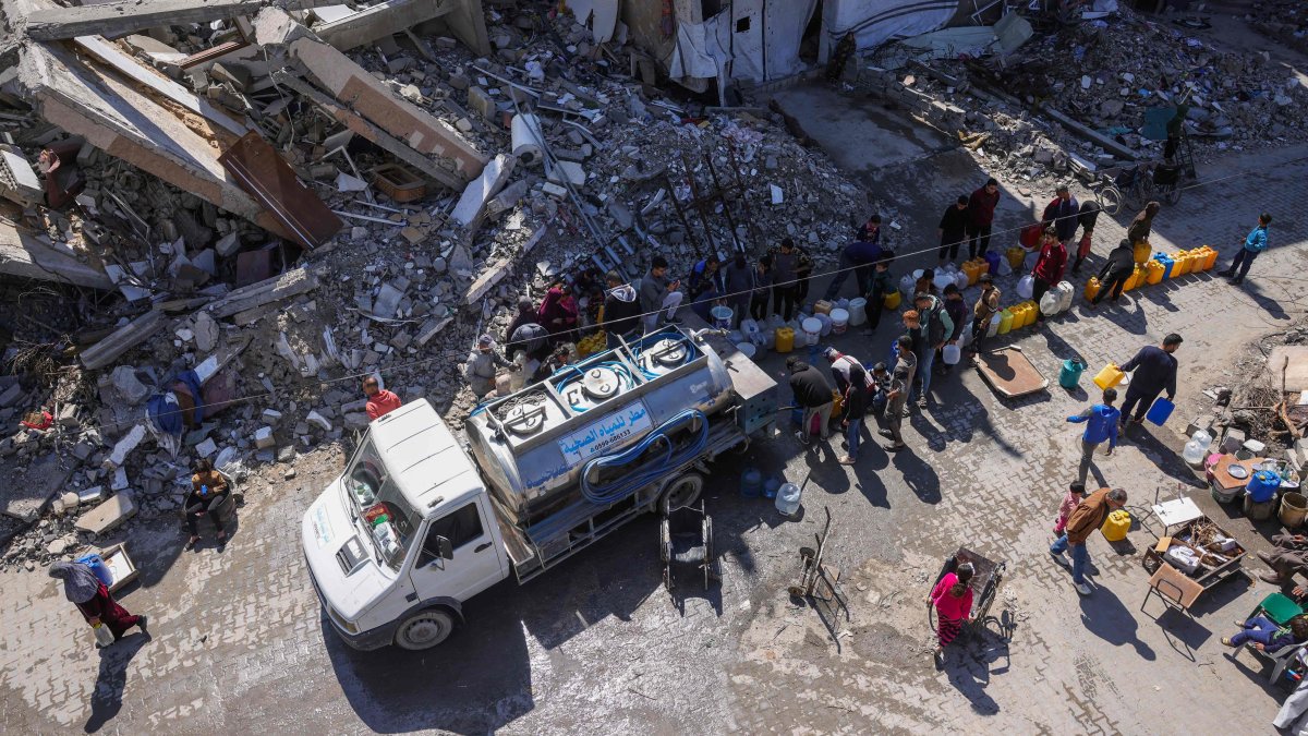Palestinians queue for water next to a distribution truck at a displacement camp west of Jabalia city in the northern Gaza Strip on March 11, 2025. (AFP Photo)