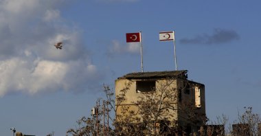 A pigeon flies next of an abandoned military guard post with a Turkish (L) and the Turkish Cypriot flags, in the northern part of Nicosia (Lefkoşa), Cyprus, Feb. 2, 2024. (AP Photo)