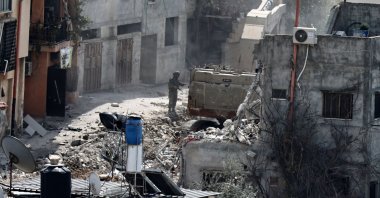 An Israeli soldier looks on as a military excavator demolishes a building in the Nur Shams camp for Palestinian refugees east of Tulkarem, amid an ongoing offensive in the occupied-West Bank, March 6, 2025. (AFP Photo)