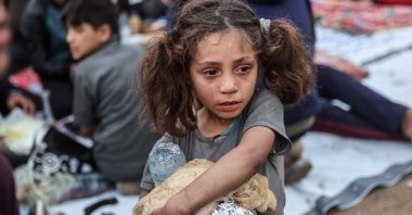 A Palestinian child carrying food cries as people gather for a mass fast-breaking iftar meal in Beit Lahia in the northern Gaza Strip, March 15, 2025. (AFP Photo)